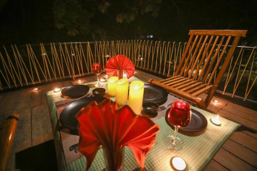 a table with plates and candles on a deck at Pench Wilderness Camp Resort in Khawāsa