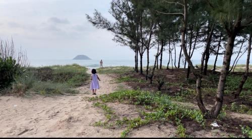 a little girl in a dress walking down a dirt road at Hồng Diễm Lagi homestay in La Gi