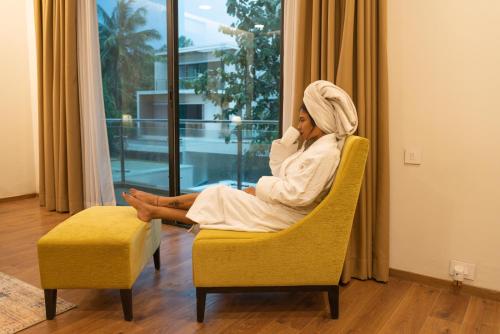 a woman sitting in a chair talking on a cell phone at Signature Club Resort in Devanhalli
