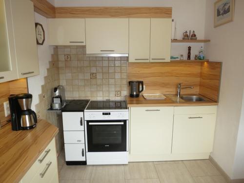 a kitchen with white cabinets and a stove and a sink at Ferienwohnung Eller in Telfes im Stubai