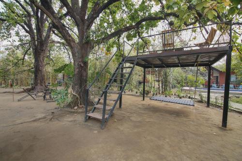 a playground with a tree with a ladder in a park at Pench Wilderness Camp Resort in Khawāsa