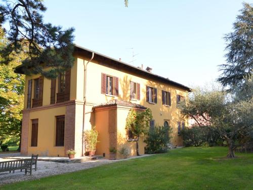 un grande edificio giallo con panchina in un parco di Elegant Holiday Home in Faenza with Garden and Pool a Faenza