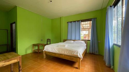 a green bedroom with a bed and a window at sokxay guerthouse in Vang Vieng
