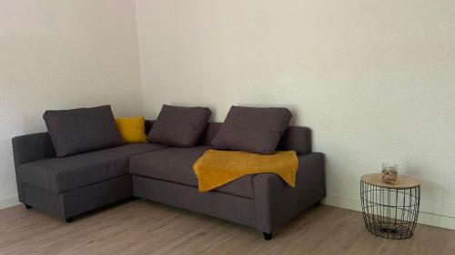 - un canapé gris avec deux oreillers et une couverture jaune dans l'établissement CAP VILLAGE, à Barbaste