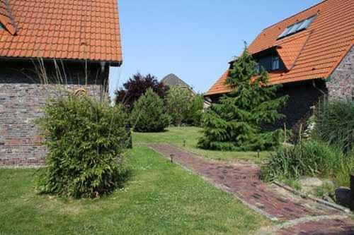 a yard with trees and a building with a house at Urlaubslust Ferienhaus 16 in Trassenheide