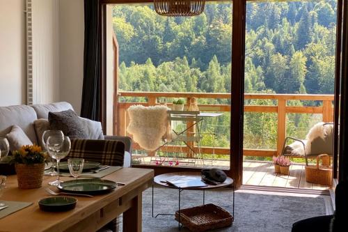ein Wohnzimmer mit einem Tisch und einem großen Fenster in der Unterkunft Les Lucioles - Charming flat in the mountains in Saint-Jean-de-Sixt