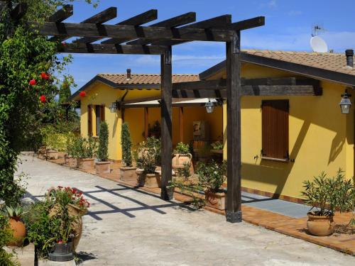 uma casa amarela com pérgola e vasos de plantas em Country House with swimming pool and garden with Mediterranean plants em Bettona
