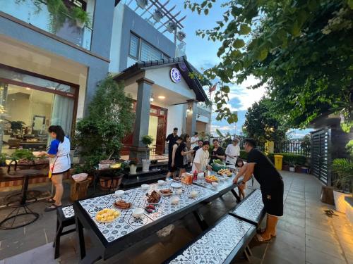木州的住宿－Chelsea Villa Moc Chau Venuestay，一群人站在桌子旁吃着食物