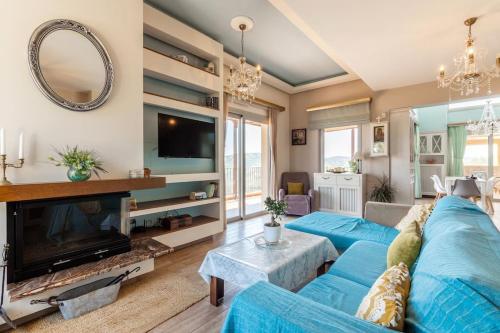 a living room with a blue couch and a tv at Serenity house near Heraklion in Stavrákia