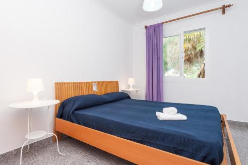 sypialnia z łóżkiem z niebieską pościelą i oknem w obiekcie Villa Sa Marina -Figuemar- w Alcudii