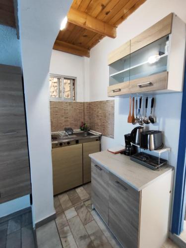 a kitchen with white walls and wooden ceilings at Oleander's Garden Traditional Cretan Cottage in Ferma