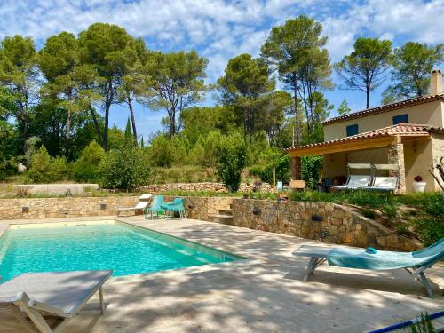 une piscine avec deux chaises et une maison dans l'établissement Piscine chauffée, tennis, Mas provençal contemporain, à Draguignan