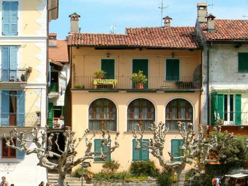 a yellow building with green doors and windows at Enticing Apartment in Stresa with Balcony Lake Views in Stresa