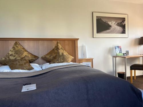 un letto con coperta blu e cuscini sopra di Hotel Alpina a Fiesch