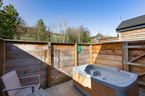 a bath tub sitting on a patio next to a fence at Hedgehog Lodge with Hot Tub in Cupar