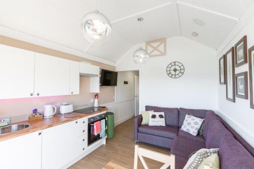 a living room with a purple couch and a kitchen at Hedgehog Lodge with Hot Tub in Cupar