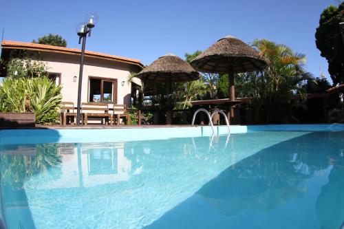 uma piscina com guarda-sóis em frente a uma casa em Pousada Mares do Santinho em Florianópolis