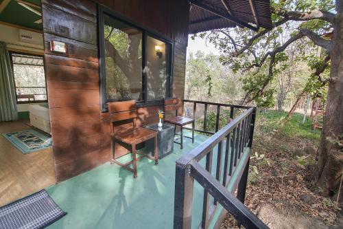 a porch of a house with a table and a chair at Pench Wilderness Camp Resort in Khawāsa