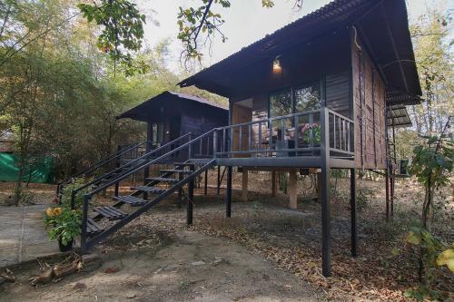 a log cabin with a staircase leading to a porch at Pench Wilderness Camp Resort in Khawāsa