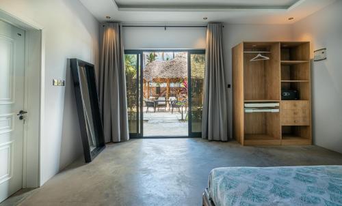 a bedroom with a bed and a door to a yard at V Hotel in Paje in Paje