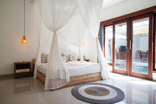 een slaapkamer met een hemelbed en een groot raam bij Villa bella wilson in Seminyak