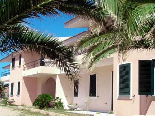a building with a palm tree in front of it at Modern Apartment in Valledoria with Swimming Pool in Codaruina