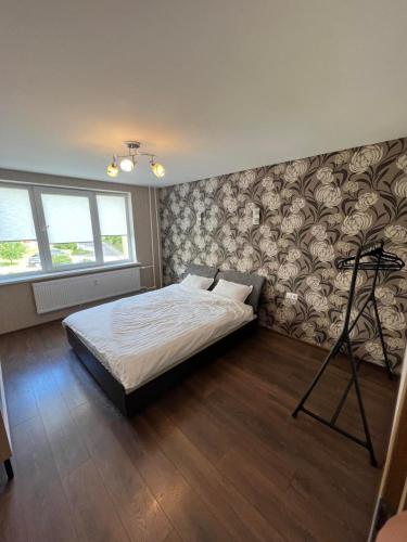 sypialnia z łóżkiem i ścianą z kwiatami w obiekcie LUNA Apartamentai w mieście Akmenė