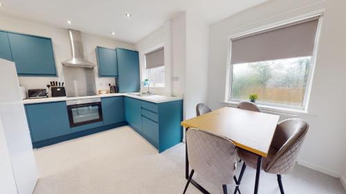 a kitchen with blue cabinets and a table and chairs at Daventry House Stockton by Horizon Stays in Stockton-on-Tees