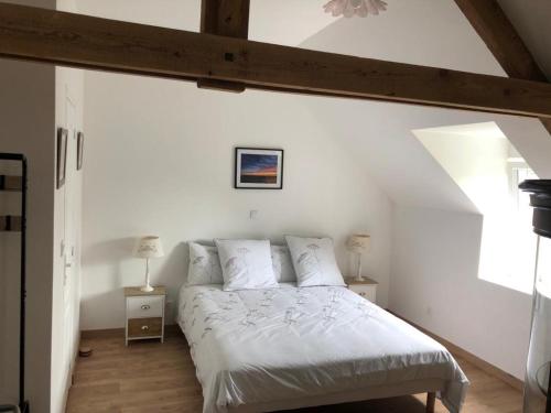 um quarto com uma cama com lençóis brancos e uma janela em Le Bout du Monde em Bricqueville-sur-Mer