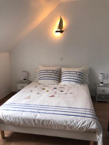 1 cama blanca con 2 almohadas y una lámpara en la pared en Le Bout du Monde, en Bricqueville-sur-Mer