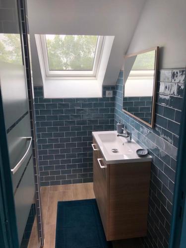 une salle de bain avec un lavabo et un miroir dans l'établissement Le Bout du Monde, à Bricqueville-sur-Mer