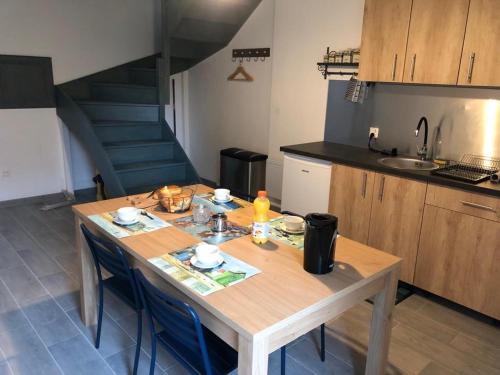 uma cozinha com uma mesa de madeira com cadeiras e uma escada em Le Bout du Monde em Bricqueville-sur-Mer