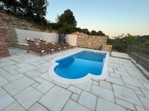 a swimming pool on a patio with chairs around it at Villa Copun with heated pool in Rab