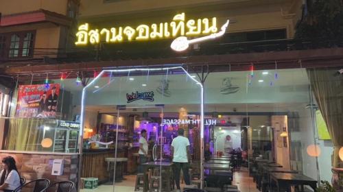 a man standing in front of a restaurant at night at อีสานจอมเทียน in Jomtien Beach