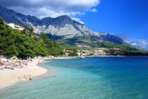 a group of people on a beach with mountains in the background at Apartment Bibo in Grubine