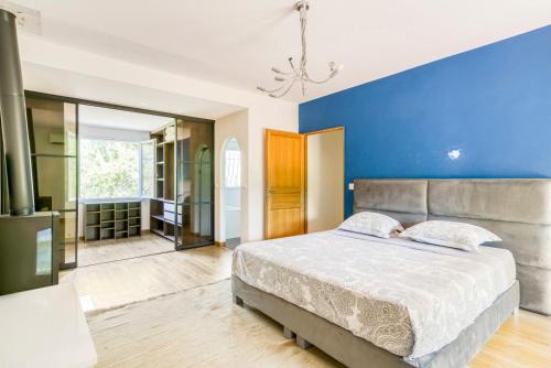 a bedroom with a bed and a blue wall at Belle villa au calme avec piscine in Antibes