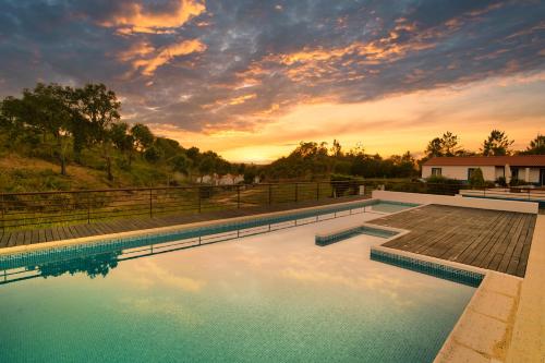 a swimming pool with a sunset in the background at Vale da Cassiopeia in Cercal