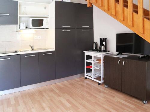 une cuisine avec des armoires noires et un four micro-ondes dans l'établissement Duplex Les Orres 1800 avec piscine, 8 pers, proche ski - FR-1-322-440, aux Orres