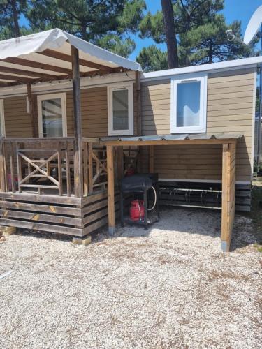 une petite maison avec une véranda et un auvent dans l'établissement Mobil Home 6 personnes Camping 5 étoiles, à Vendays-Montalivet