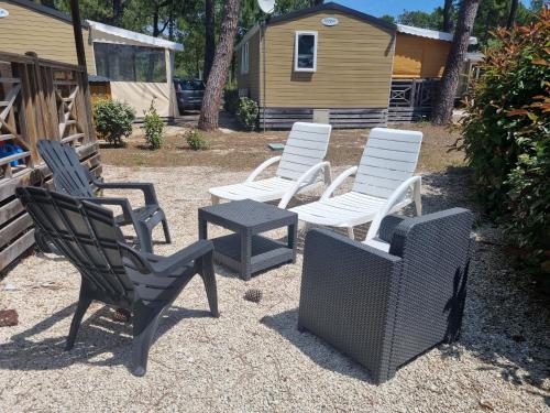 un grupo de sillas y una mesa en un patio en Mobil Home 6 personnes Camping 5 étoiles, en Vendays-Montalivet