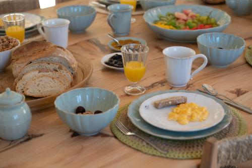 una mesa de madera cubierta con platos y cuencos de productos para el desayuno en Vale da Cassiopeia, en Cercal