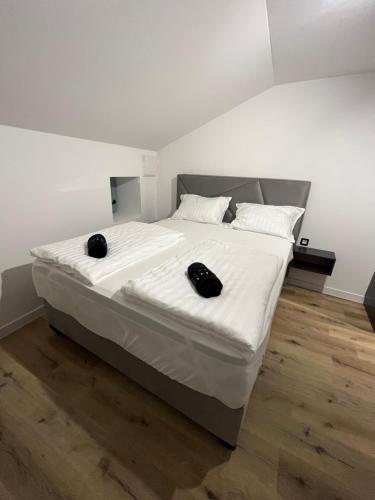 a large white bed with two black objects on it at Villa Copun with heated pool in Rab