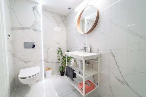 a white bathroom with a toilet and a sink at Apartamenty Prusa in Mikołajki