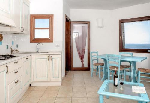 a kitchen with a table and blue chairs in it at Residence La Marmorata in Santa Teresa Gallura