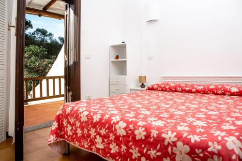 a bedroom with a red bed with a red and white blanket at Residence La Marmorata in Santa Teresa Gallura