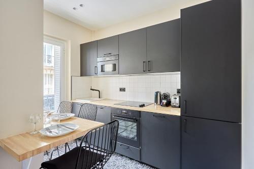 une cuisine avec des armoires noires et une table avec des chaises dans l'établissement Apartment Invalide by Studio prestige, à Paris