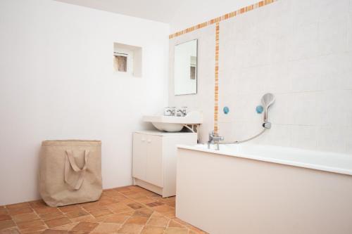 a white bathroom with a sink and a tub and a mirror at La croix des vignes in Brossay