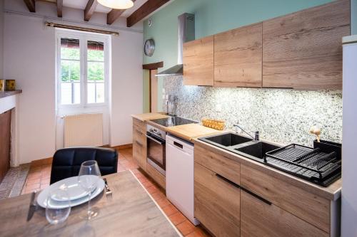 une cuisine avec des armoires en bois, un évier et une table dans l'établissement La croix des vignes, à Brossay