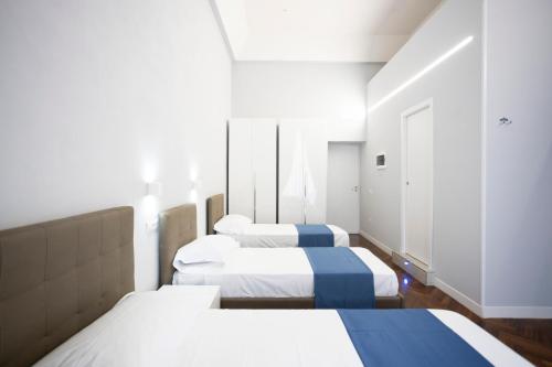 3 Betten in einem Zimmer in Weiß und Blau in der Unterkunft La Chambre Duomo in Neapel