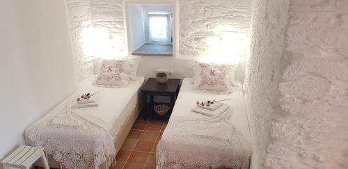 Habitación con 2 camas, ropa de cama blanca y ventana. en Est 1852 - Katoi Art, en Ándros